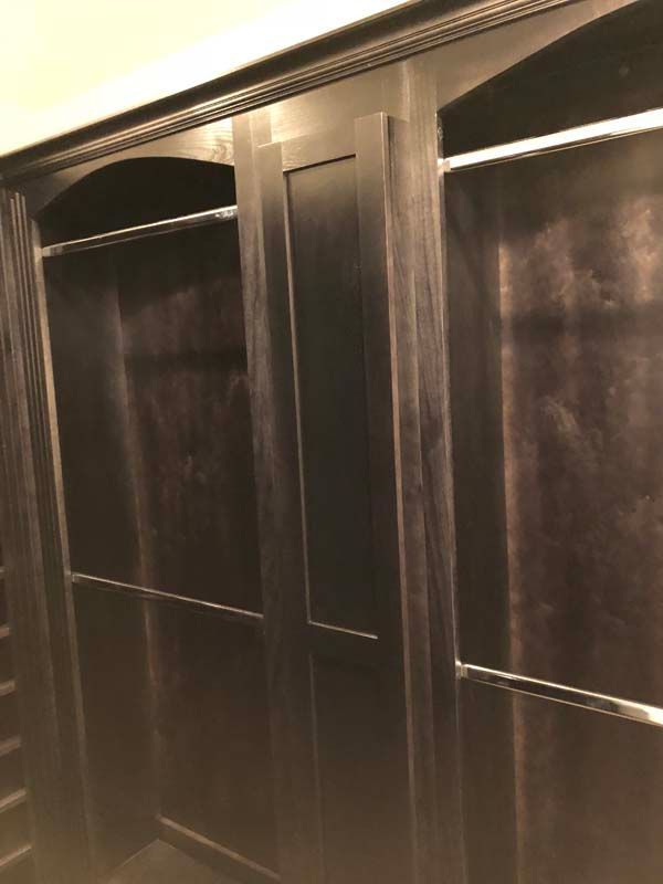 Dark wood closet with sliding doors, two clothing rods.
