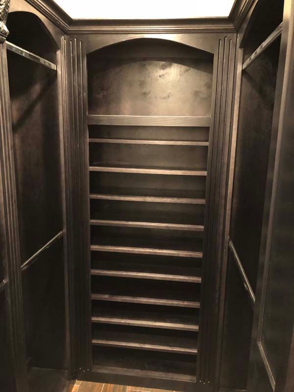 Dark wood closet interior with shelves and hanging rods.