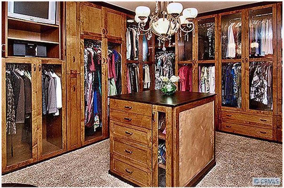Walk-in closet with dark wood cabinets, center island, and clothing racks.