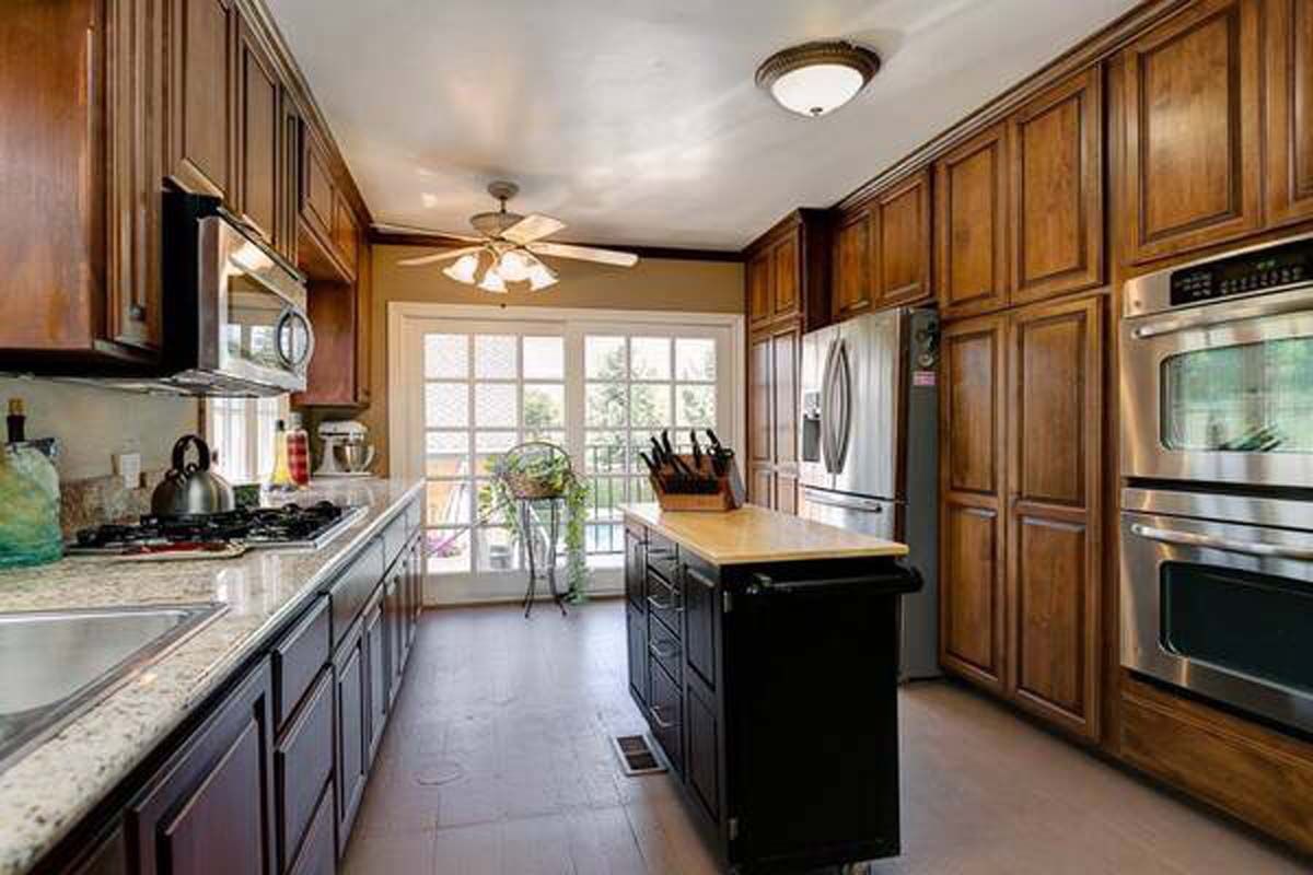Kitchen with wooden cabinets, stainless steel appliances, island, and doors to a balcony.