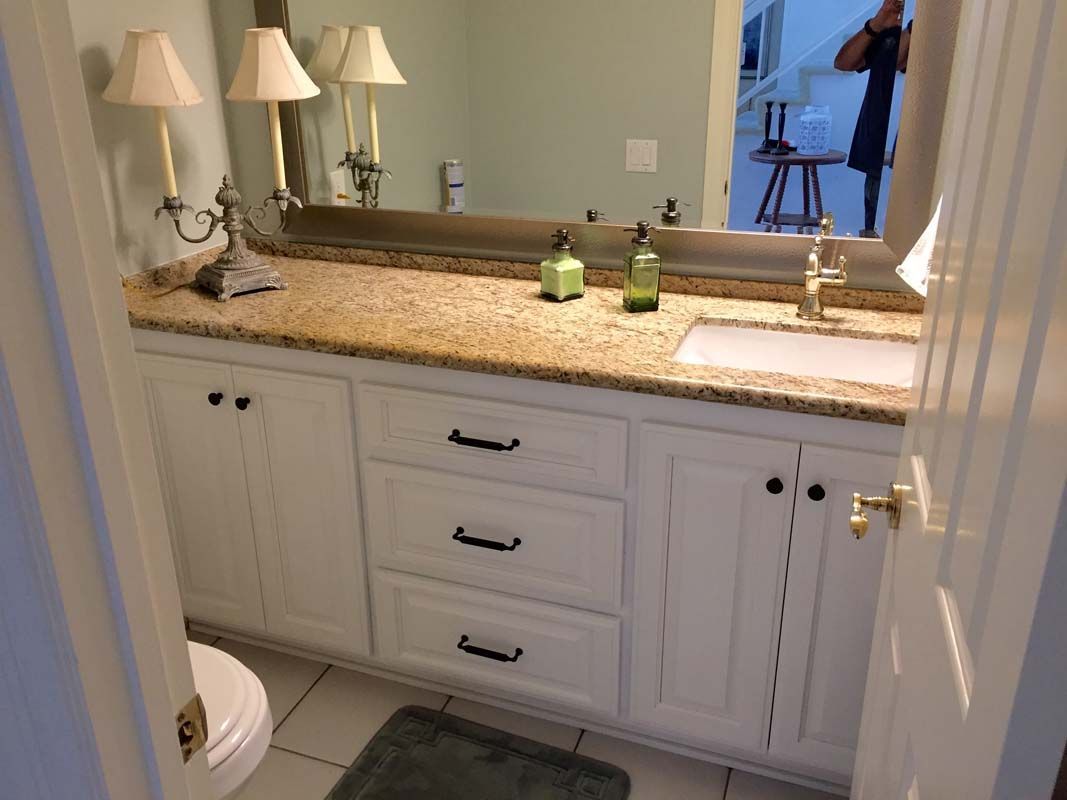 Bathroom vanity with white cabinets, granite countertop, and mirror.