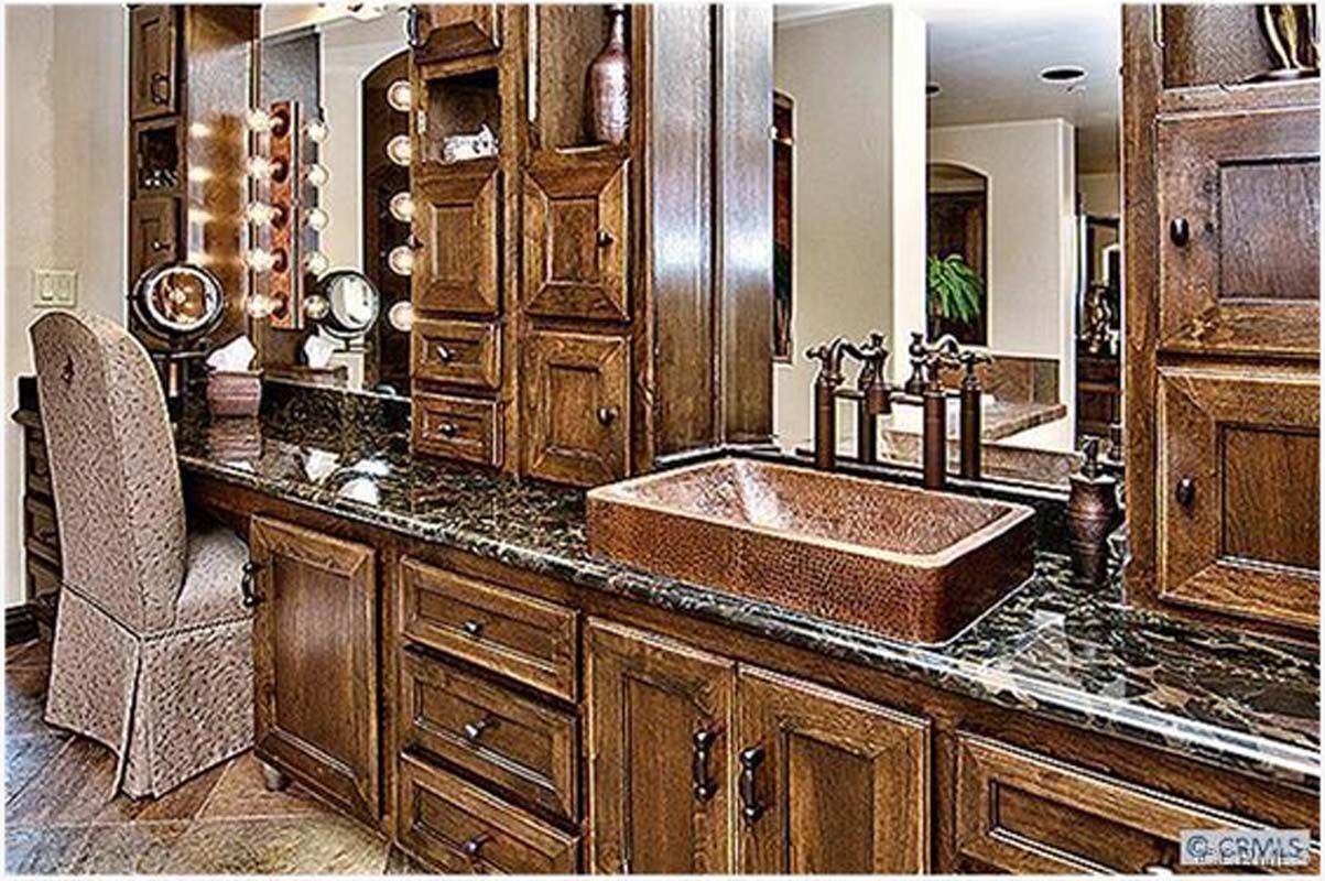 Vanity area with brown cabinets, granite countertop, copper sink, and chair.