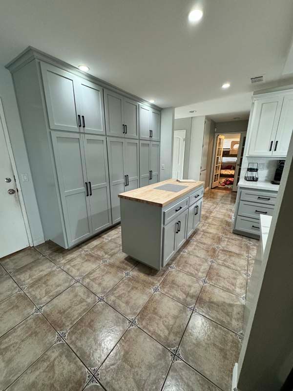 Gray kitchen with large cabinets, island, and tile floor.