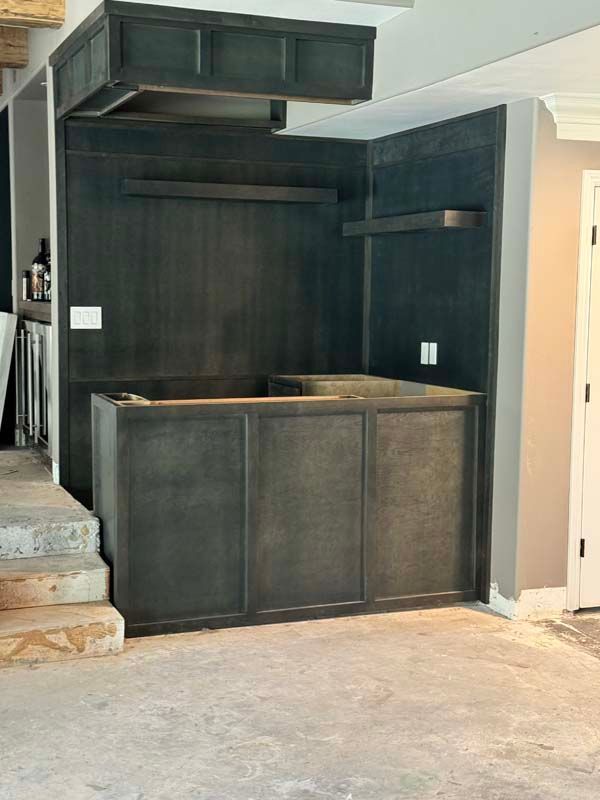 Dark stained wood home bar under construction; cabinets, shelves, and overhead structure.
