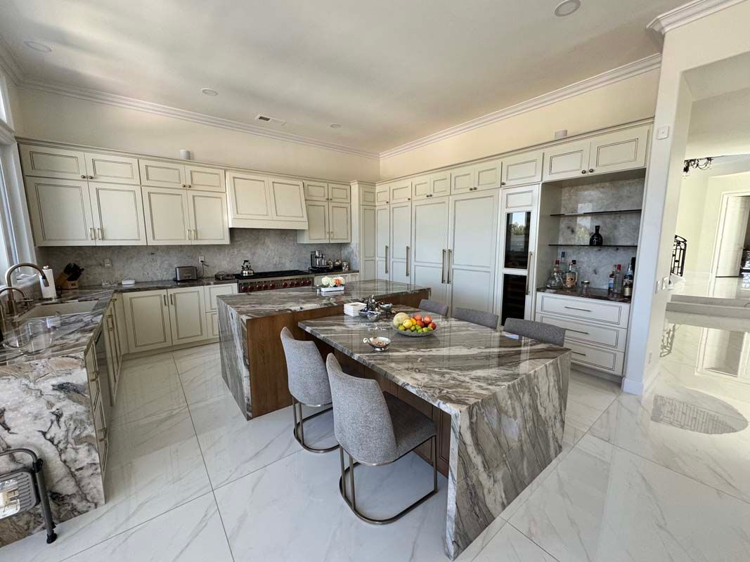 Spacious white kitchen with marble countertops, central island, cabinets, and a built-in shelf.