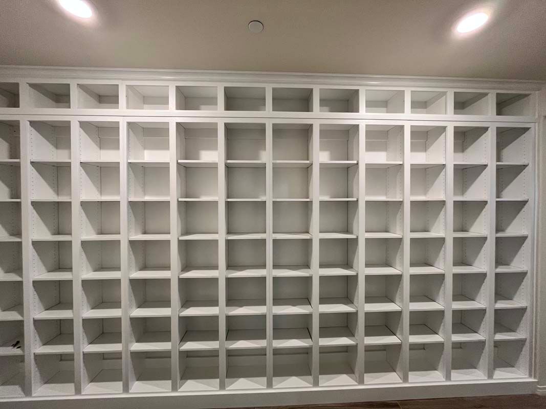 White built-in shelving unit with many square compartments, mounted on a wall.