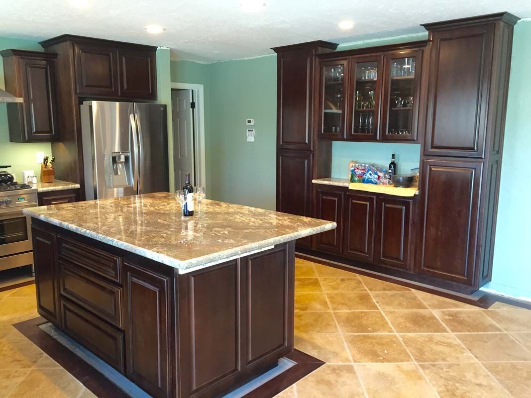 Kitchen with dark wood cabinets, a granite island, and stainless steel appliances.