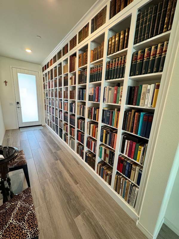 A long hallway with built-in bookshelves filled with books. Light wood flooring and white trim.