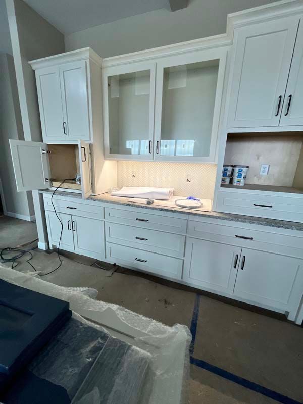 White kitchen cabinets with drawers and doors, countertop, and built-in lighting.