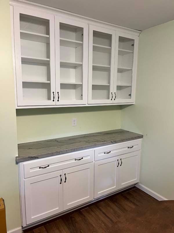 White built-in cabinetry with glass-fronted upper cabinets and solid-door base cabinets; light countertop.