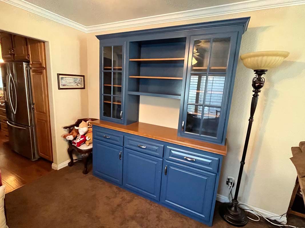 Blue hutch with glass doors, brown countertop, and three cabinets. A floor lamp is to the side.