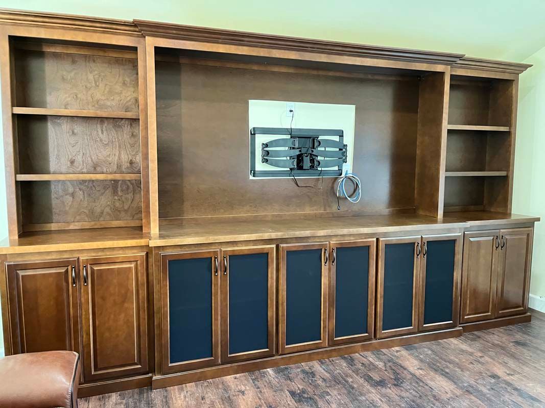 Wooden entertainment center with shelves, cabinets, and a mounted TV bracket.