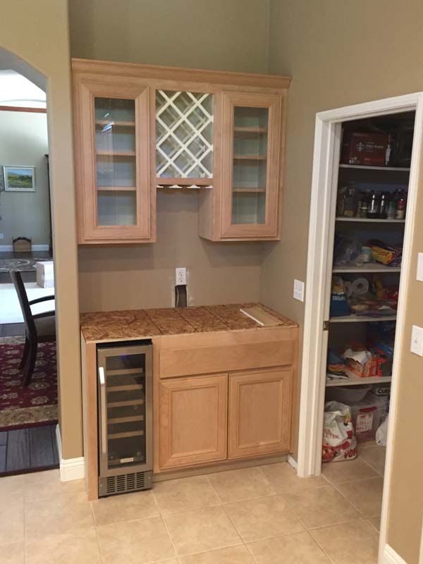 A built-in kitchen cabinet with a wine rack, mini-fridge, and pantry to the right.