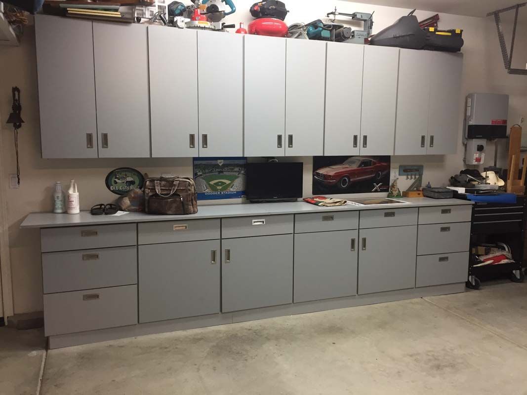 Garage storage cabinets, gray, with countertop, holding tools and miscellaneous items.