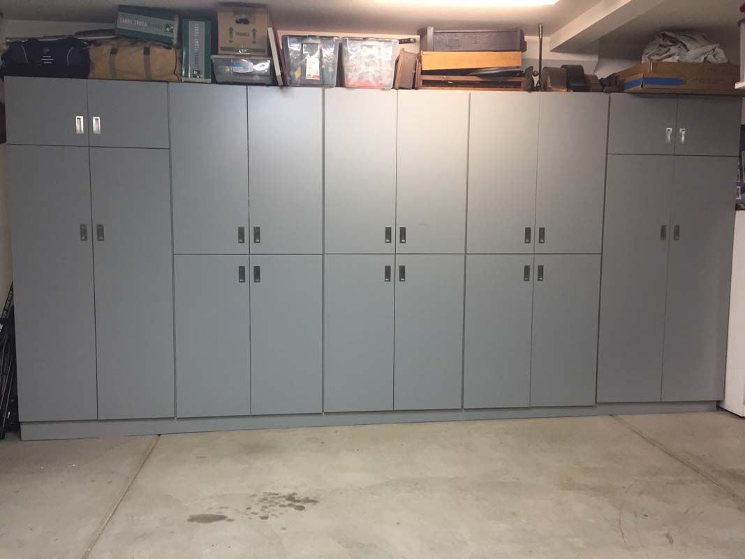 Gray storage cabinets line a garage wall, with items stored on top.