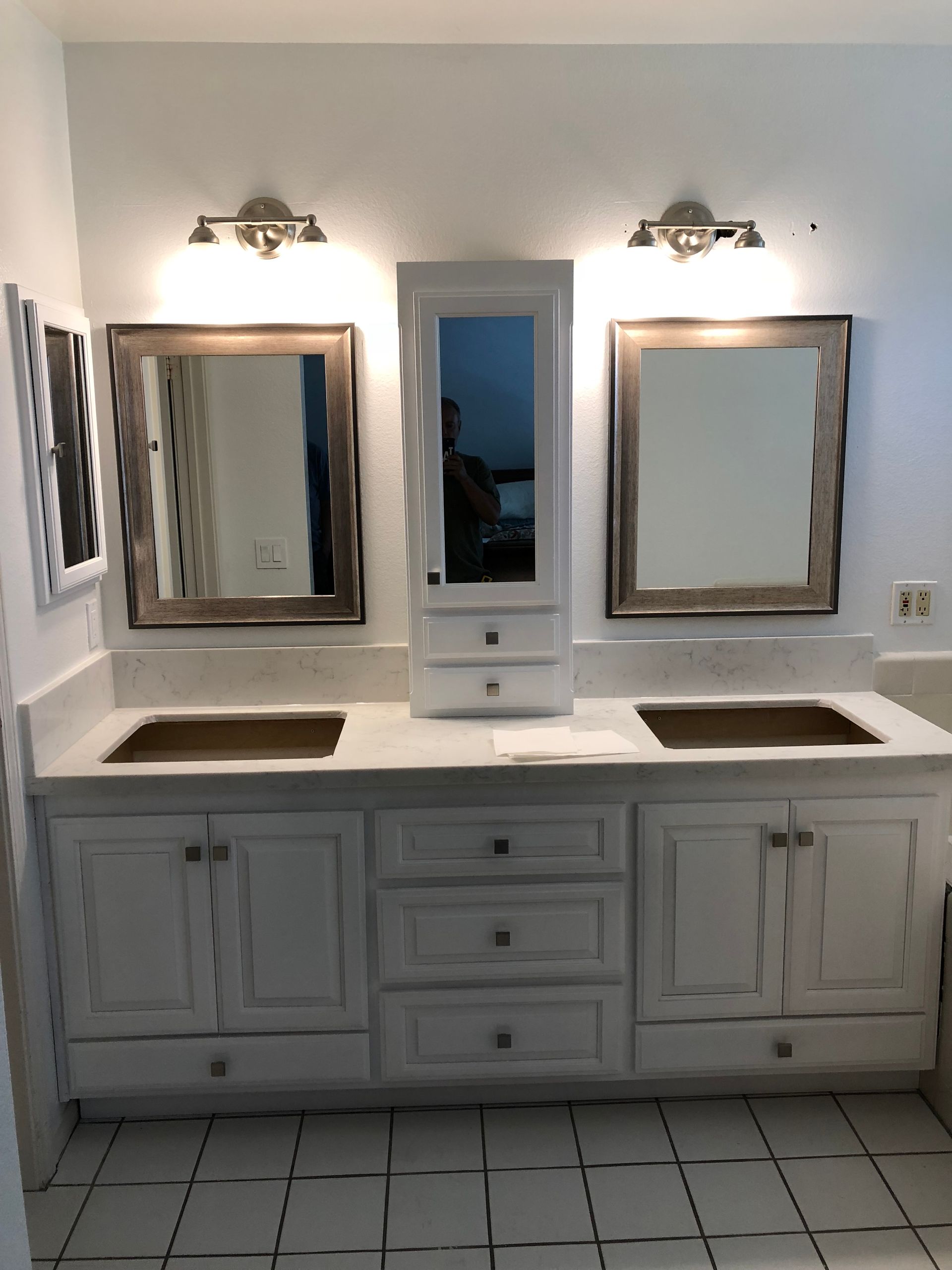 White bathroom vanity with two sinks, mirrors, and a tall cabinet.