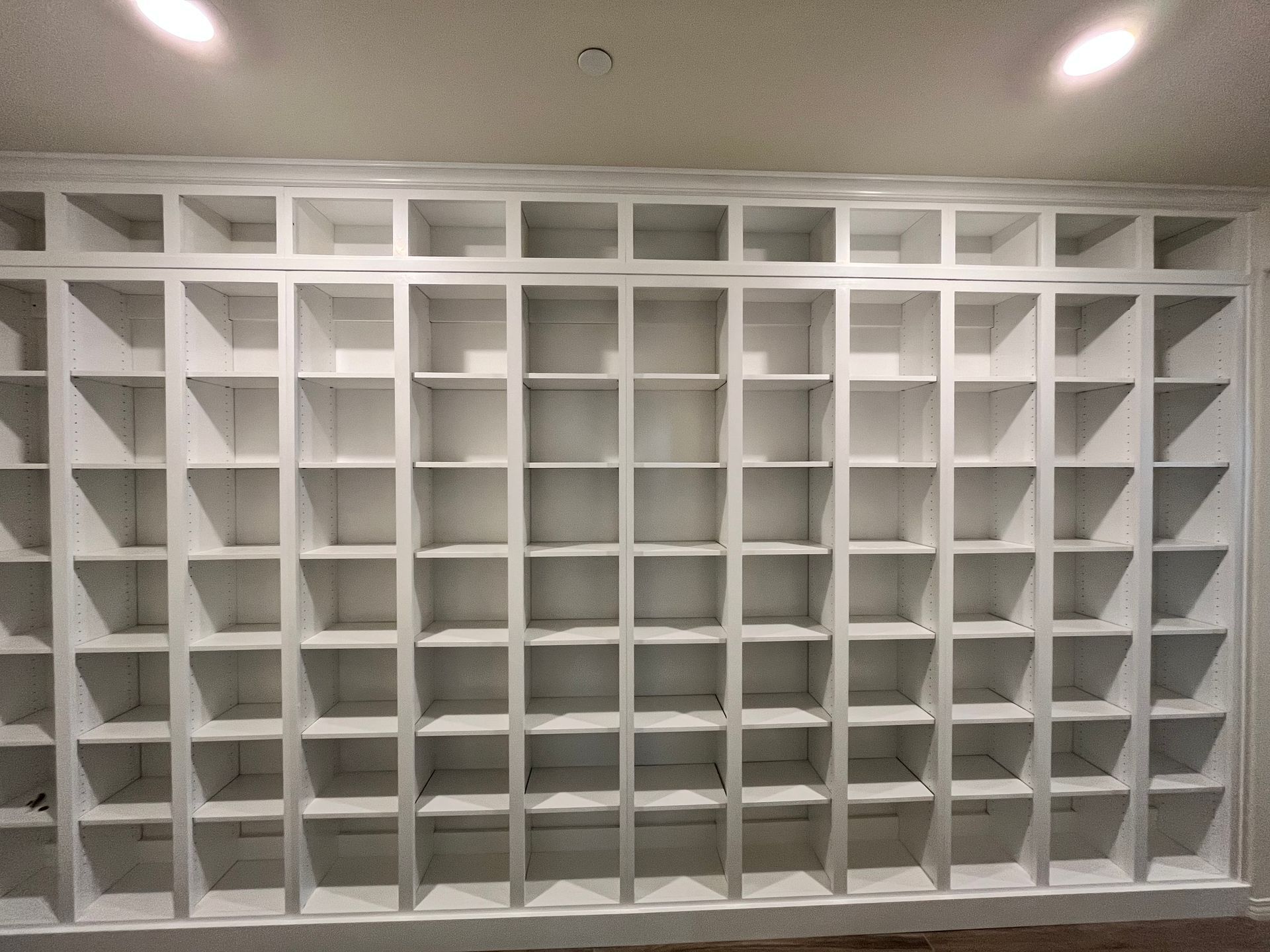 White built-in shelving unit filling a wall. Cubbies arranged in rows and columns.