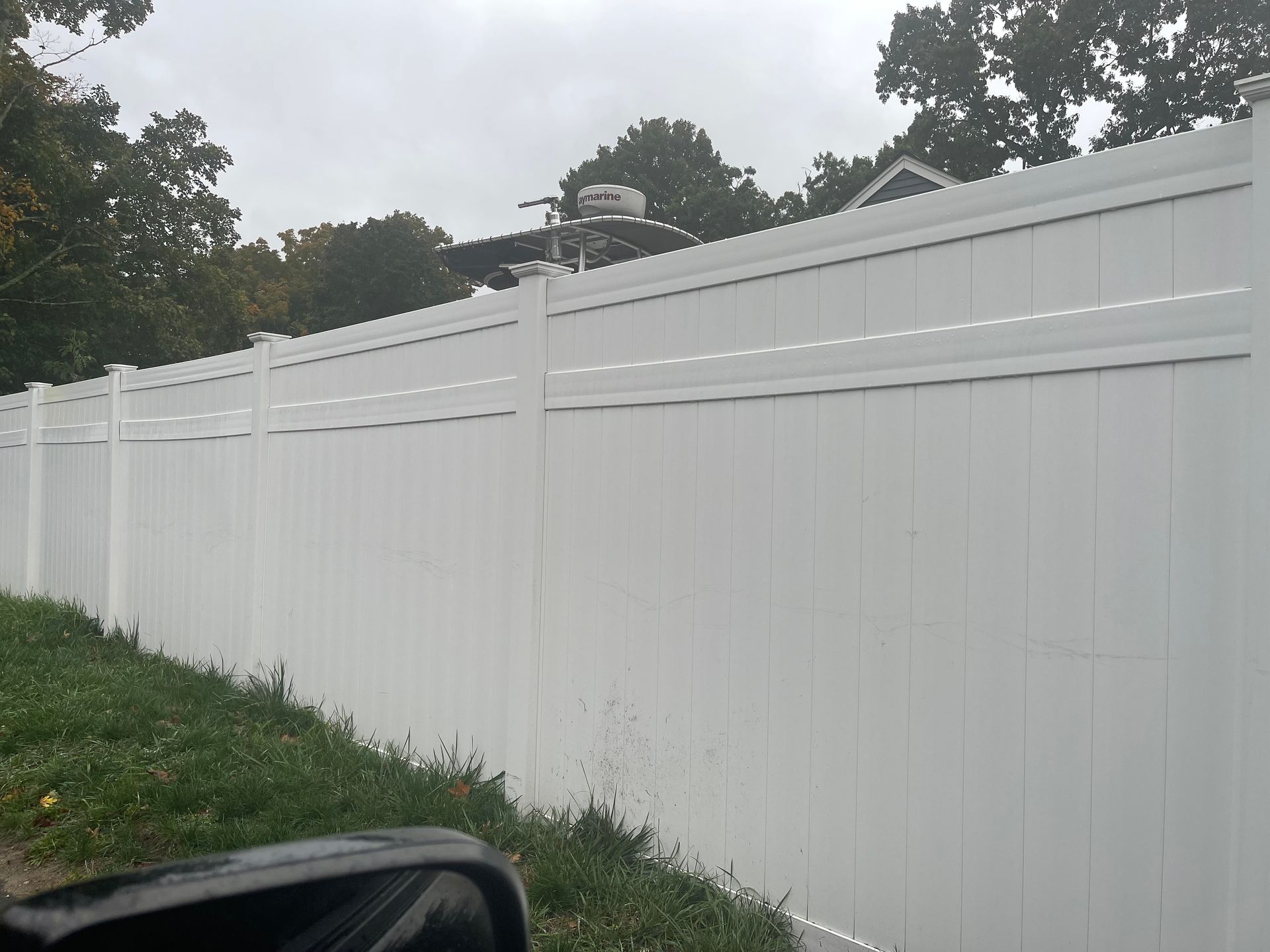 A white fence is sitting on top of a lush green field.
