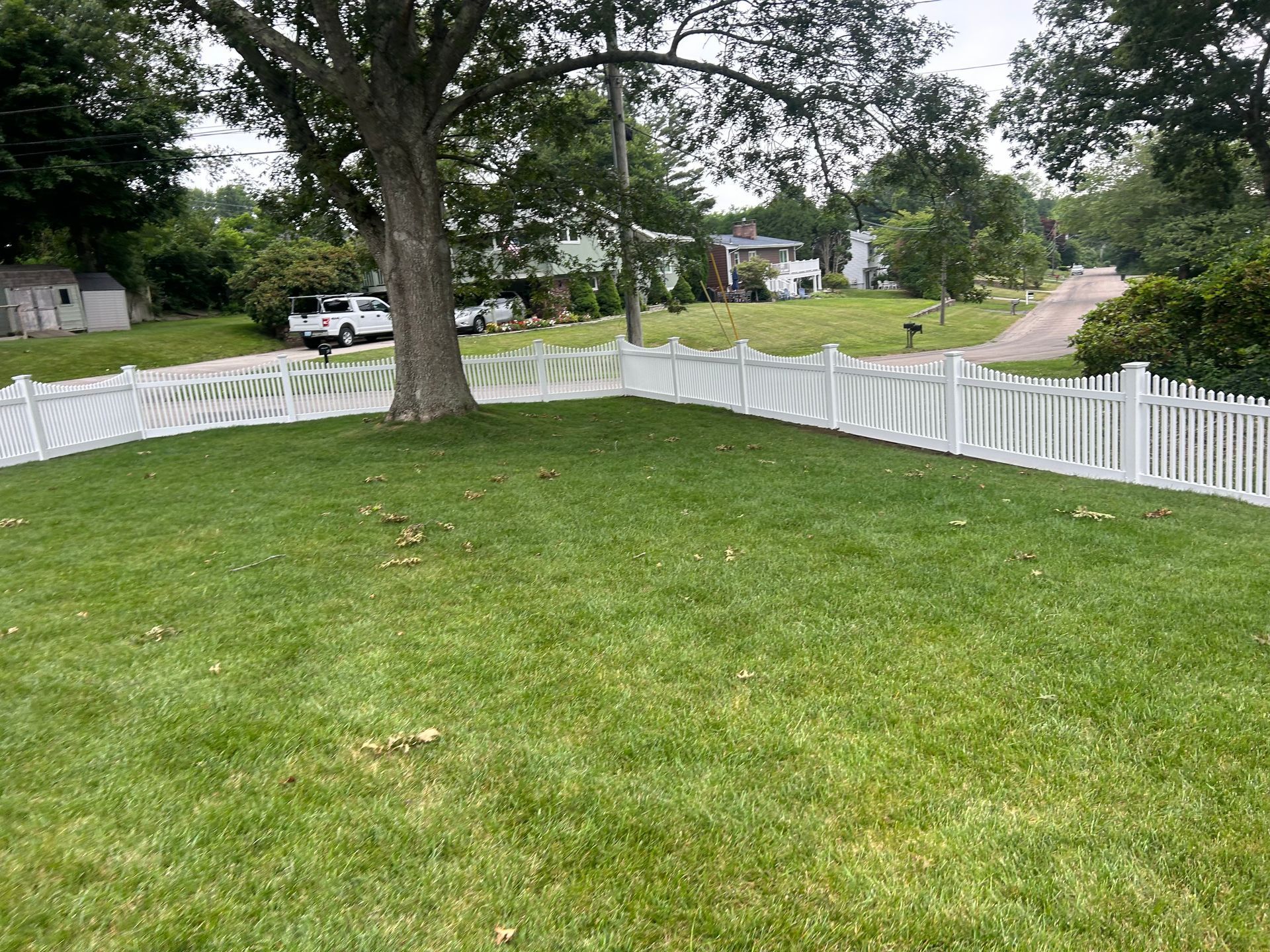 A white picket fence surrounds a lush green yard.