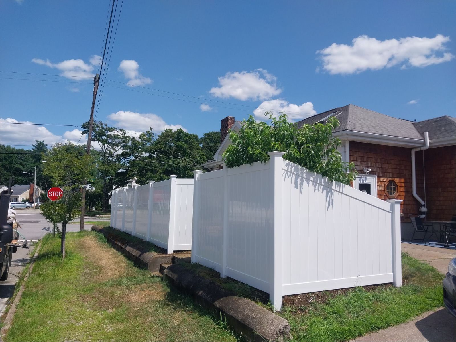 A white fence surrounds a grassy yard in front of a house.