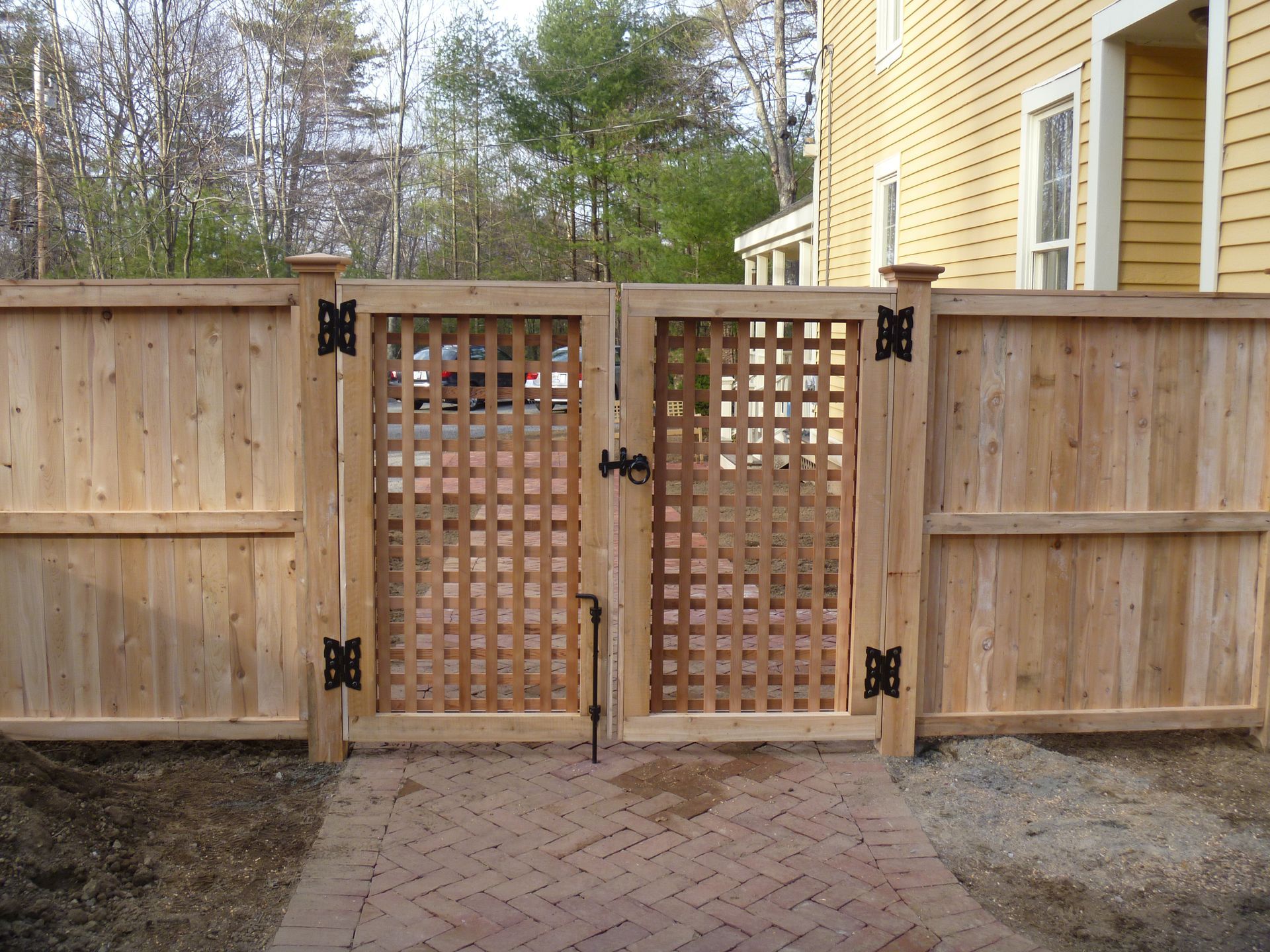 A wooden fence with a gate in front of a yellow house