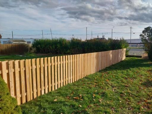 A wooden picket fence surrounds a lush green field.