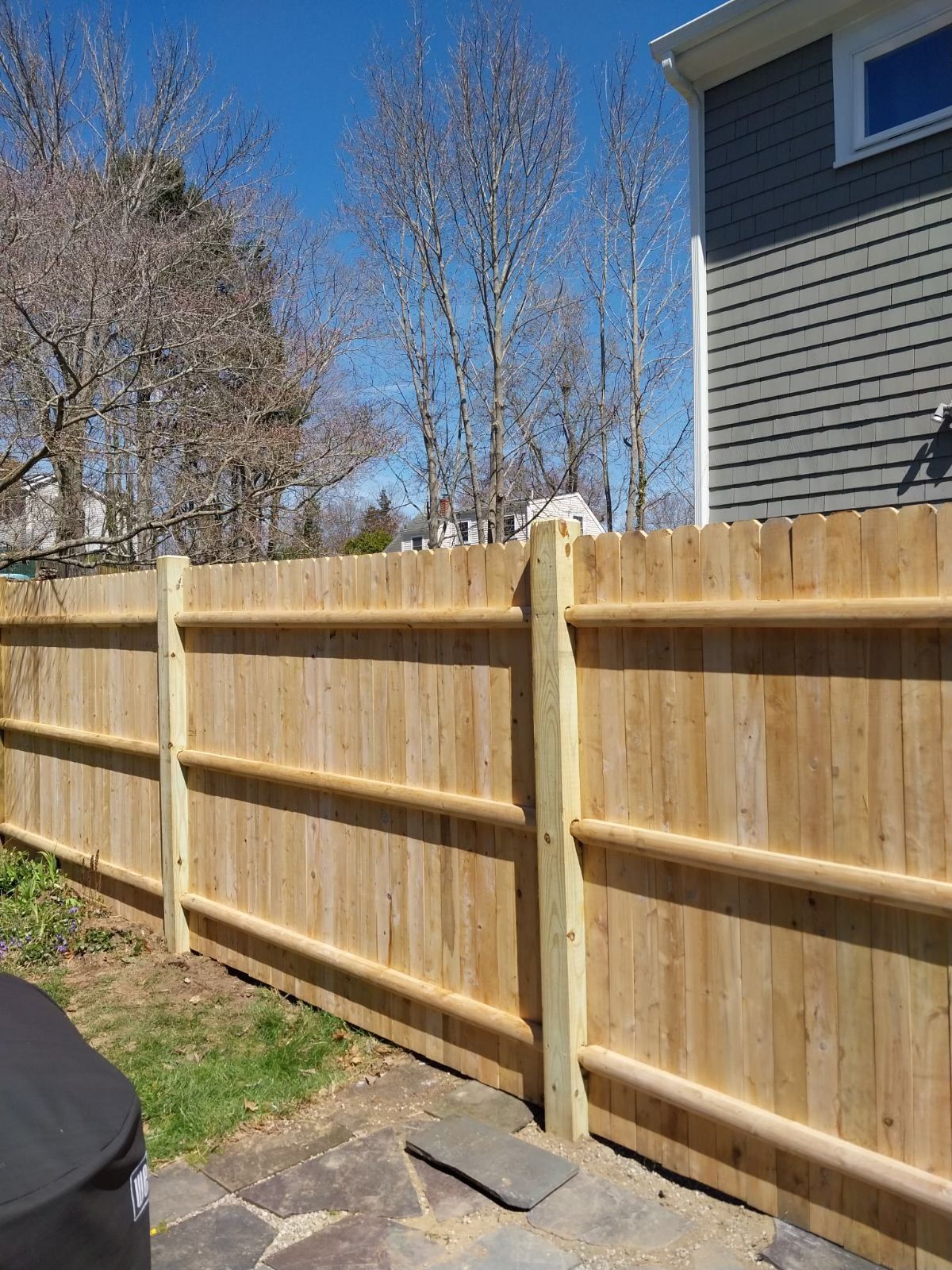 A wooden fence is in the backyard of a house.