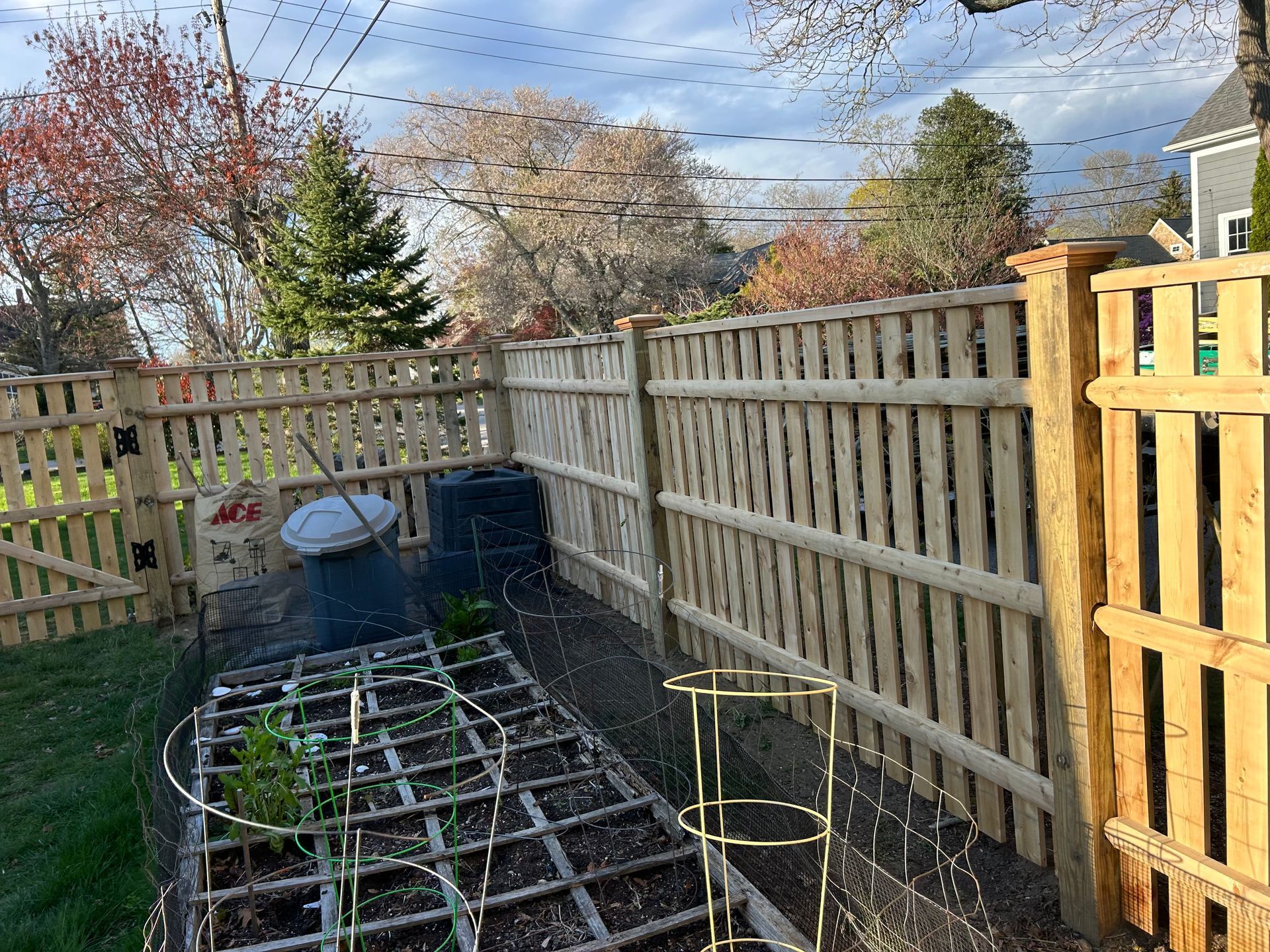 A wooden fence surrounds a garden with plants growing in it.