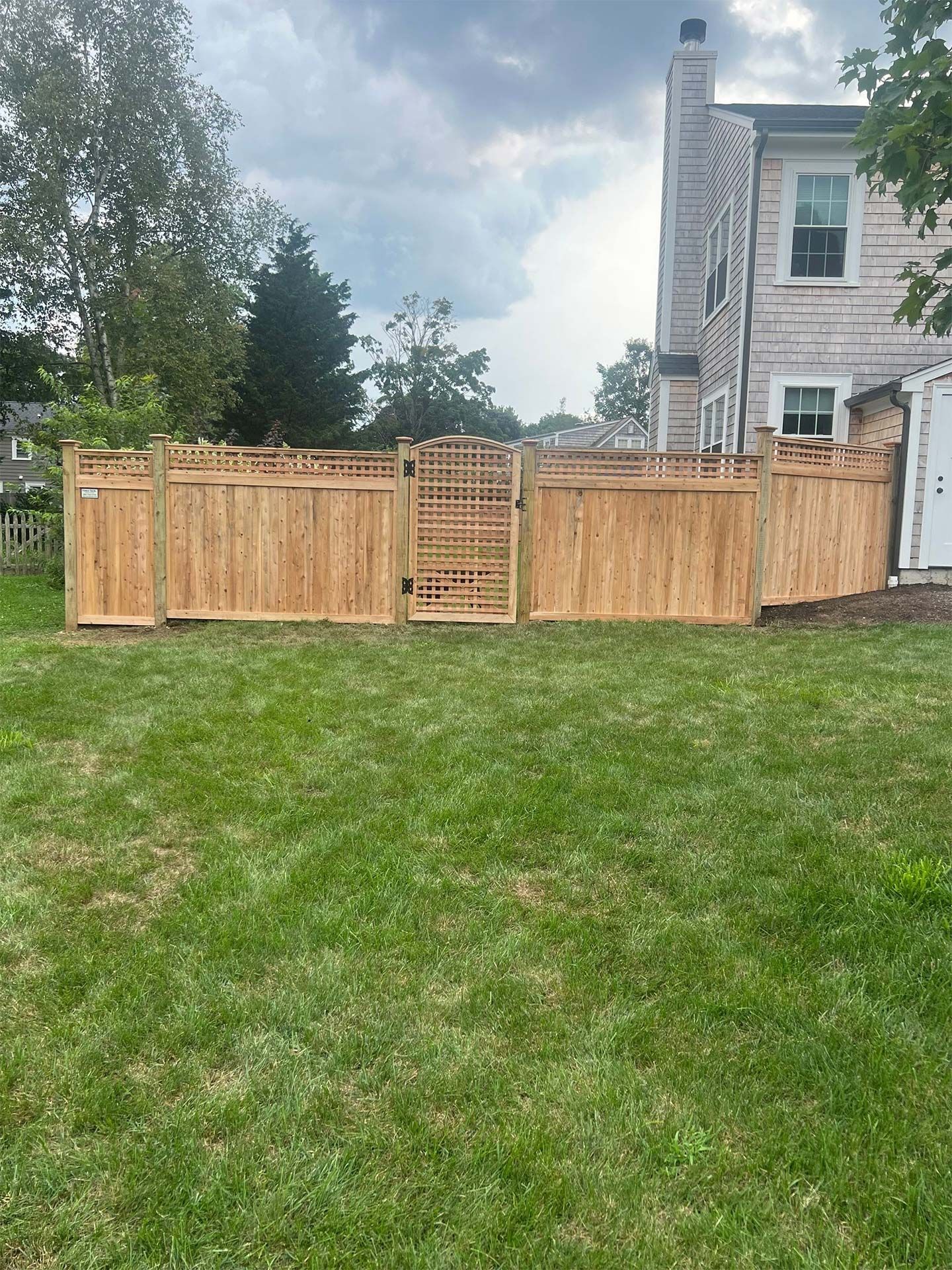 A wooden fence is in the backyard of a house.
