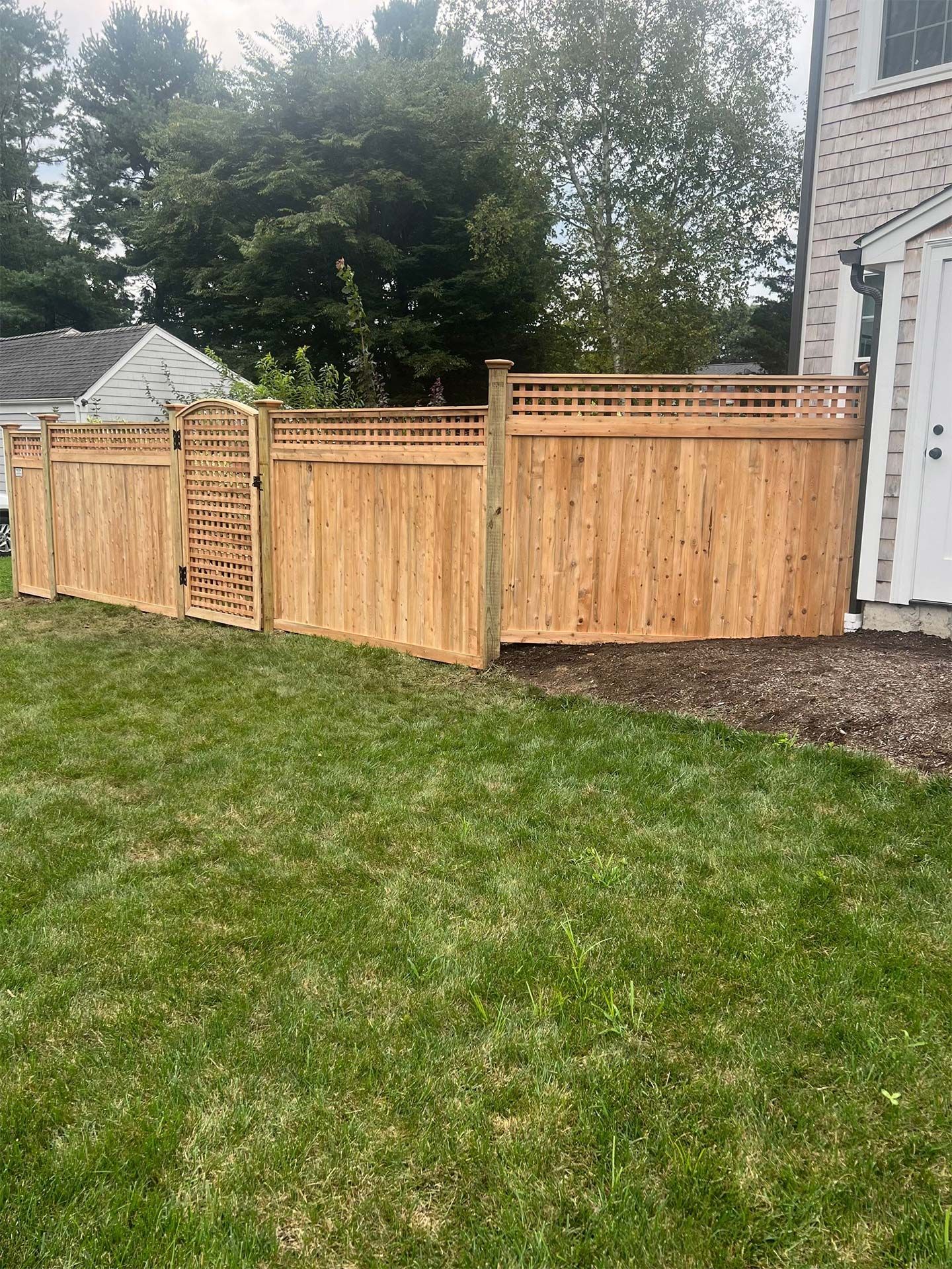 A wooden fence is in the backyard of a house.