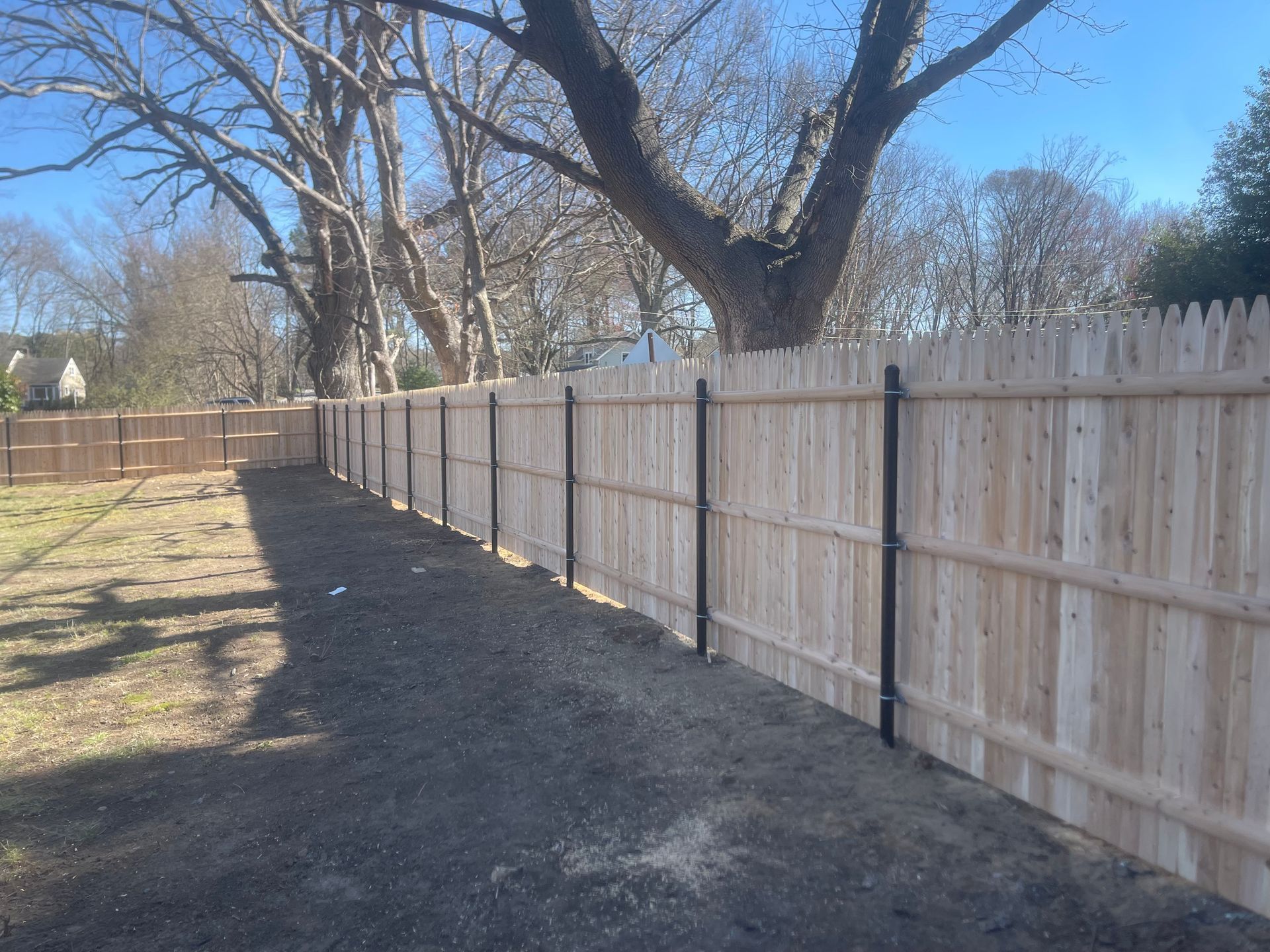 A wooden fence in a backyard with trees in the background.