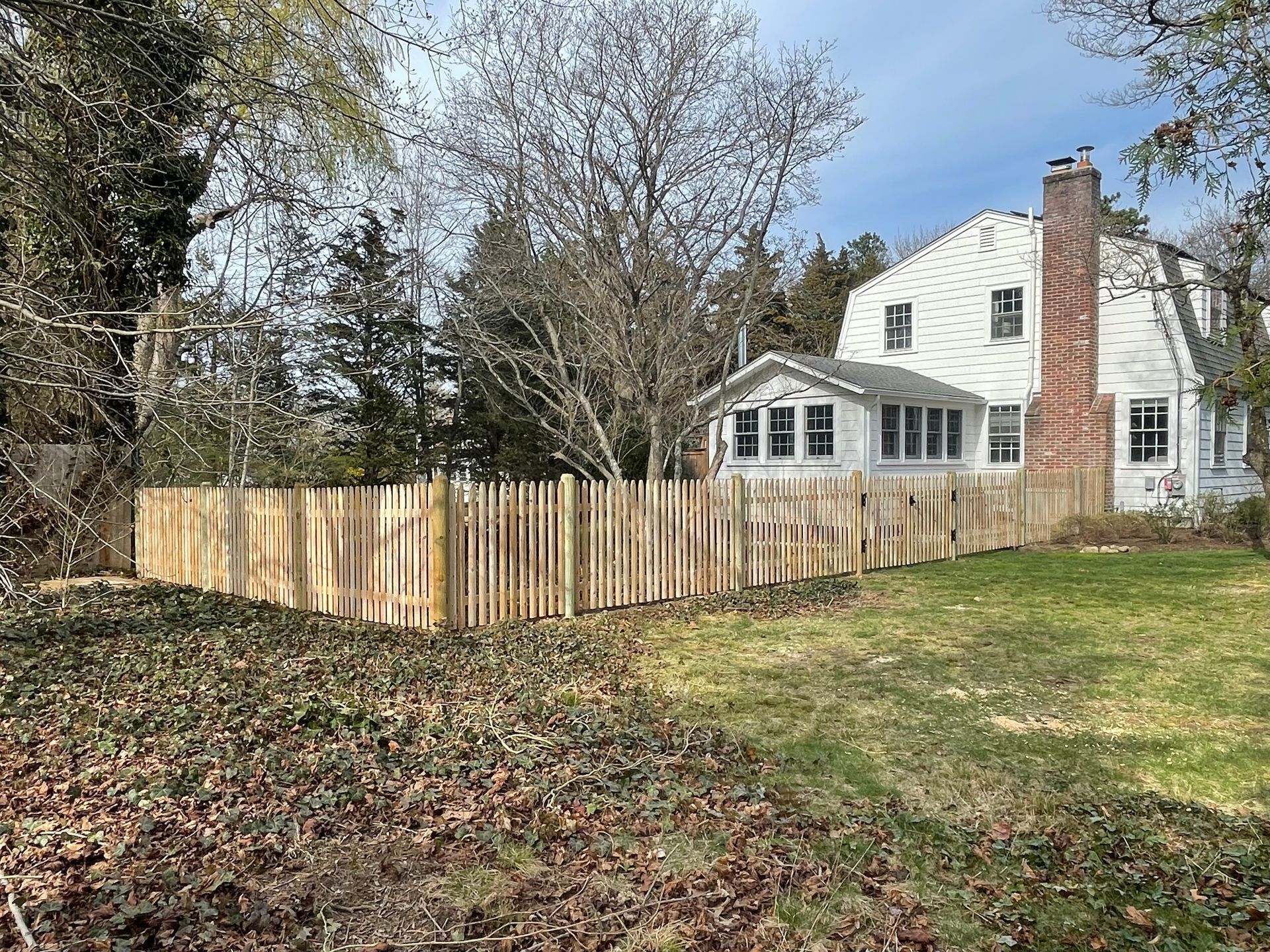 A large white house with a wooden fence in front of it.