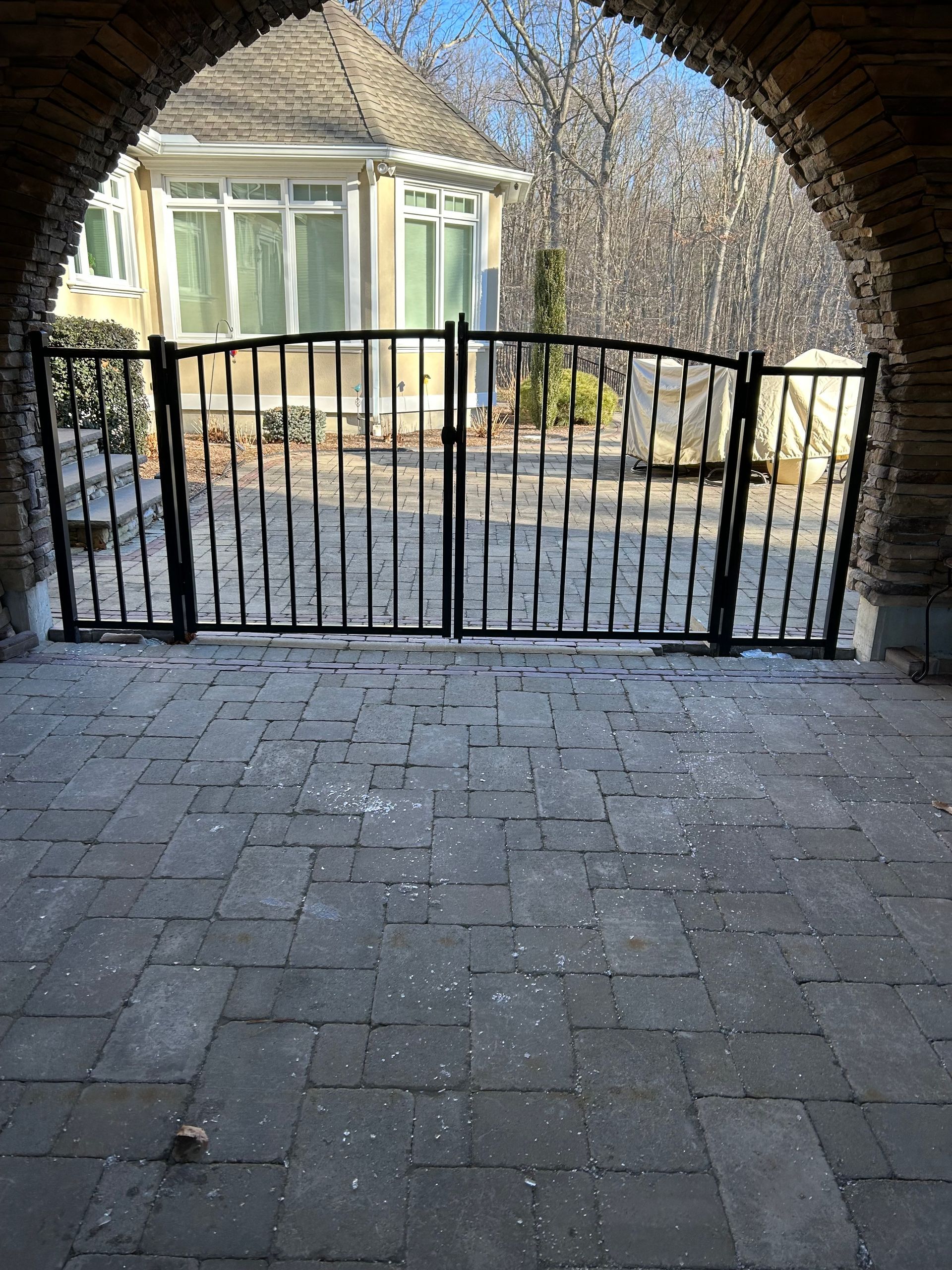 A brick archway with a wrought iron gate leading to a house