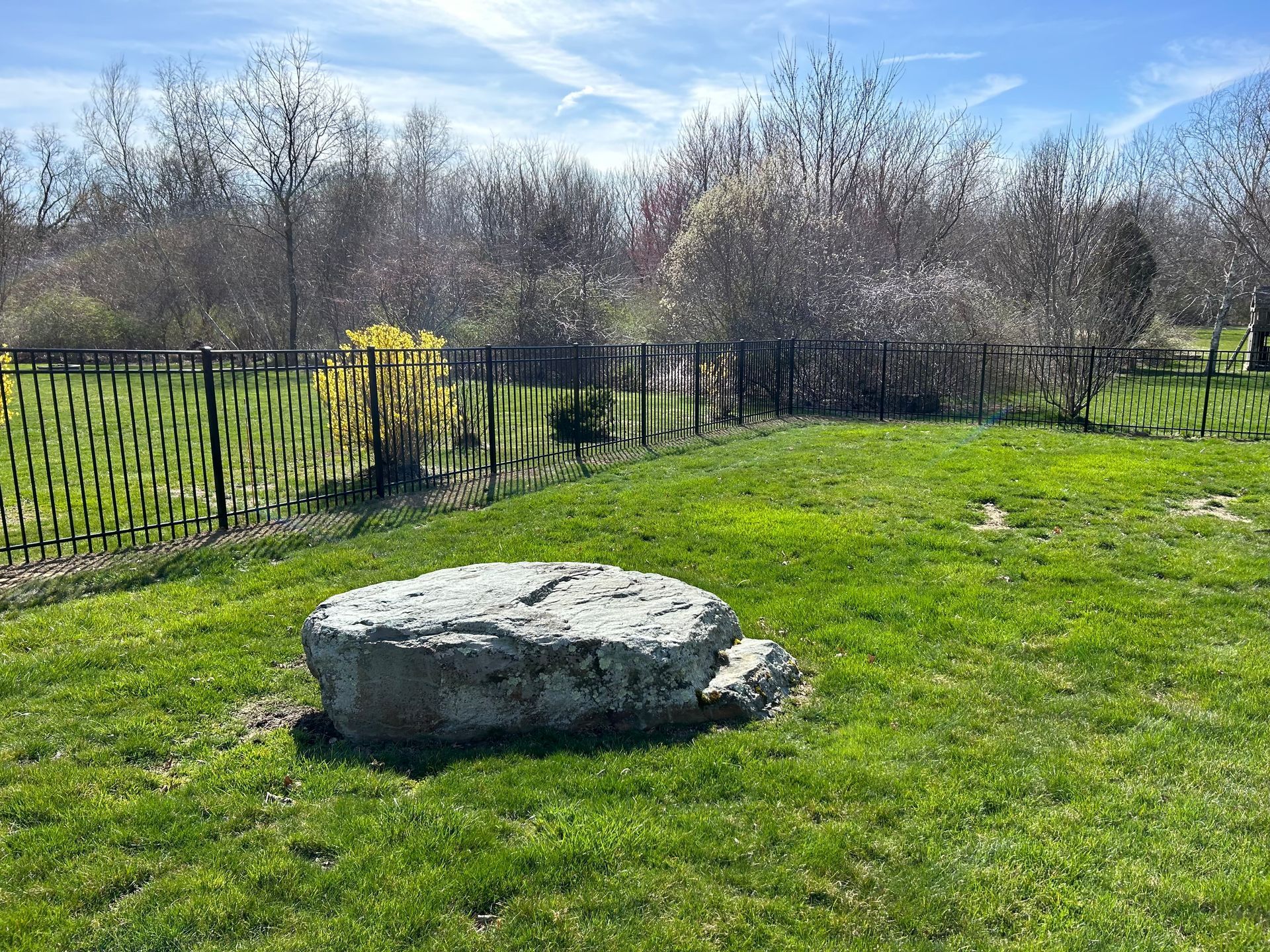 A large rock is sitting in the middle of a lush green field.