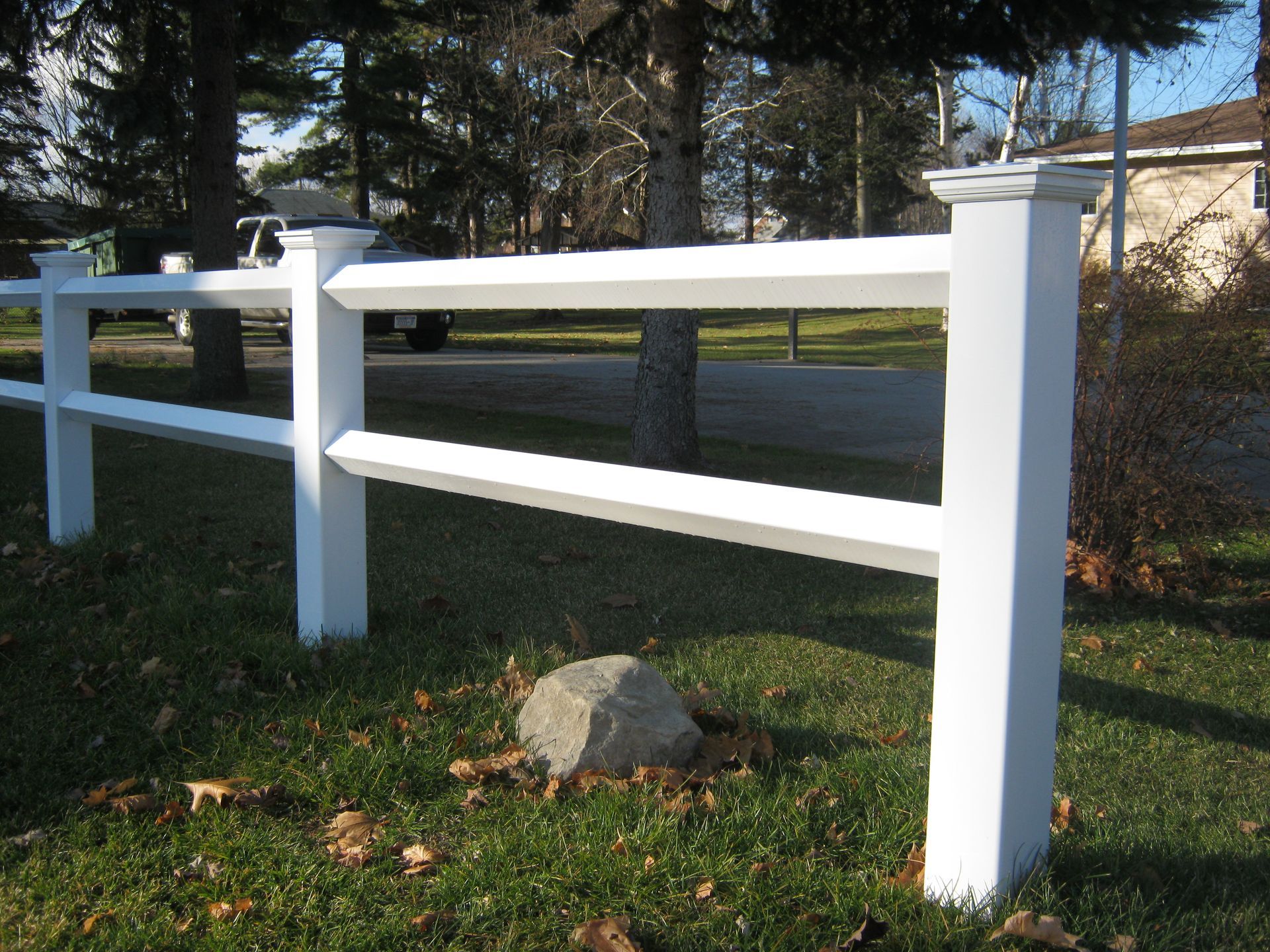 A white fence with a rock in the middle of it