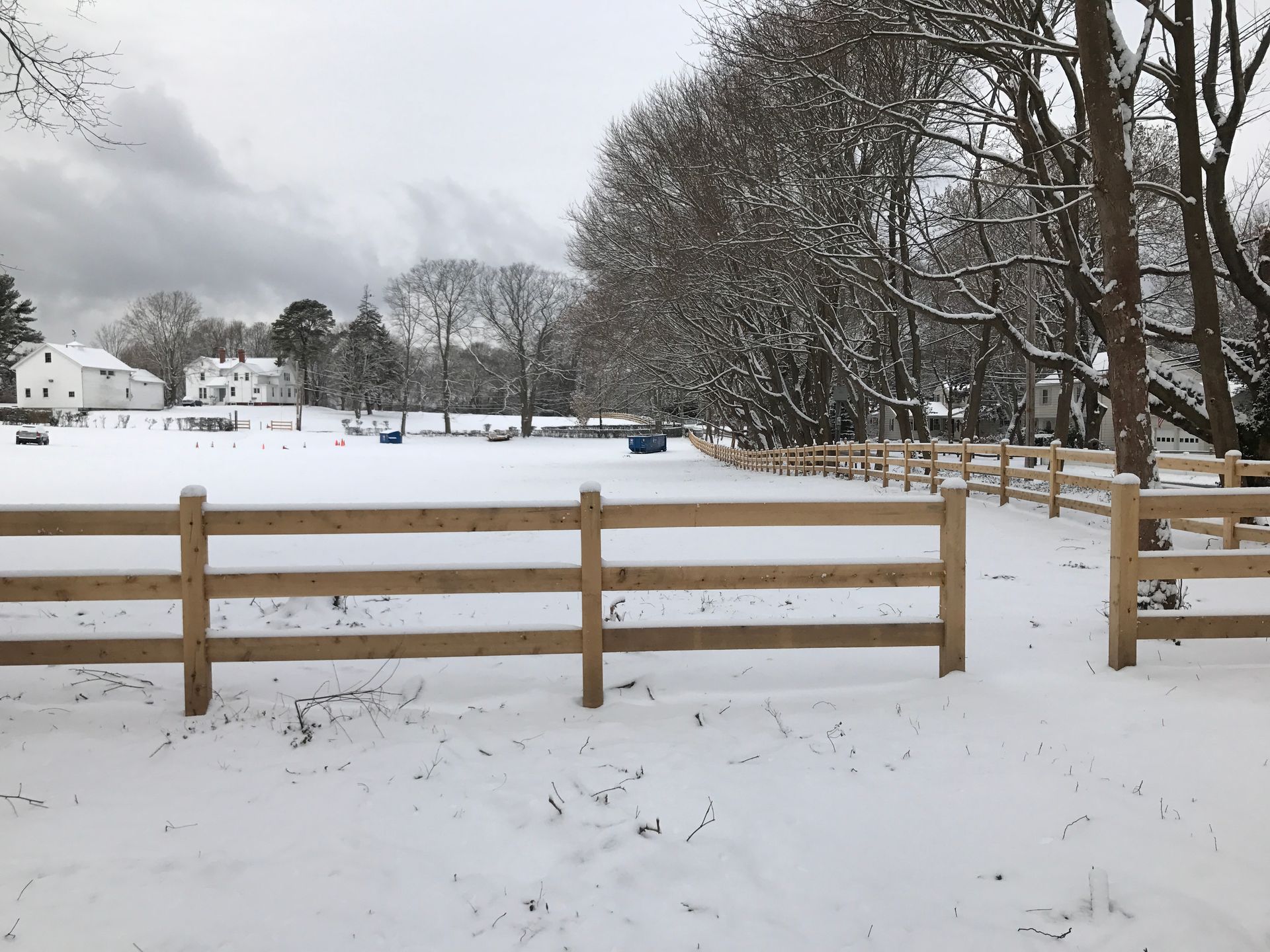 A snowy field with a wooden fence in the foreground
