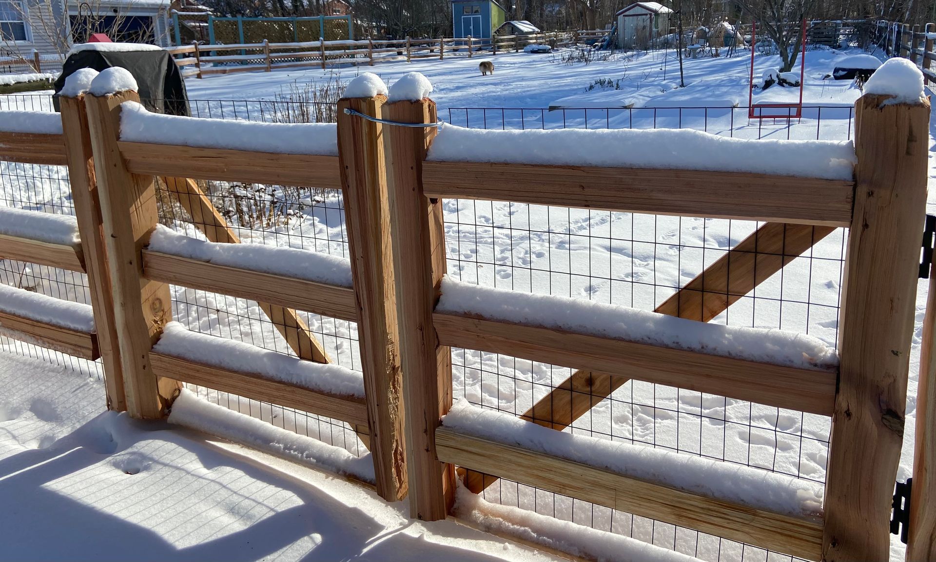 A wooden fence is covered in snow on a snowy day