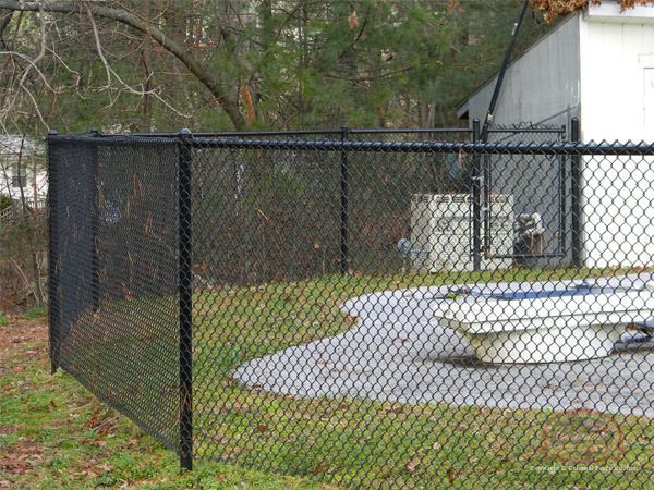 A black chain link fence surrounds a swimming pool and a picnic table.