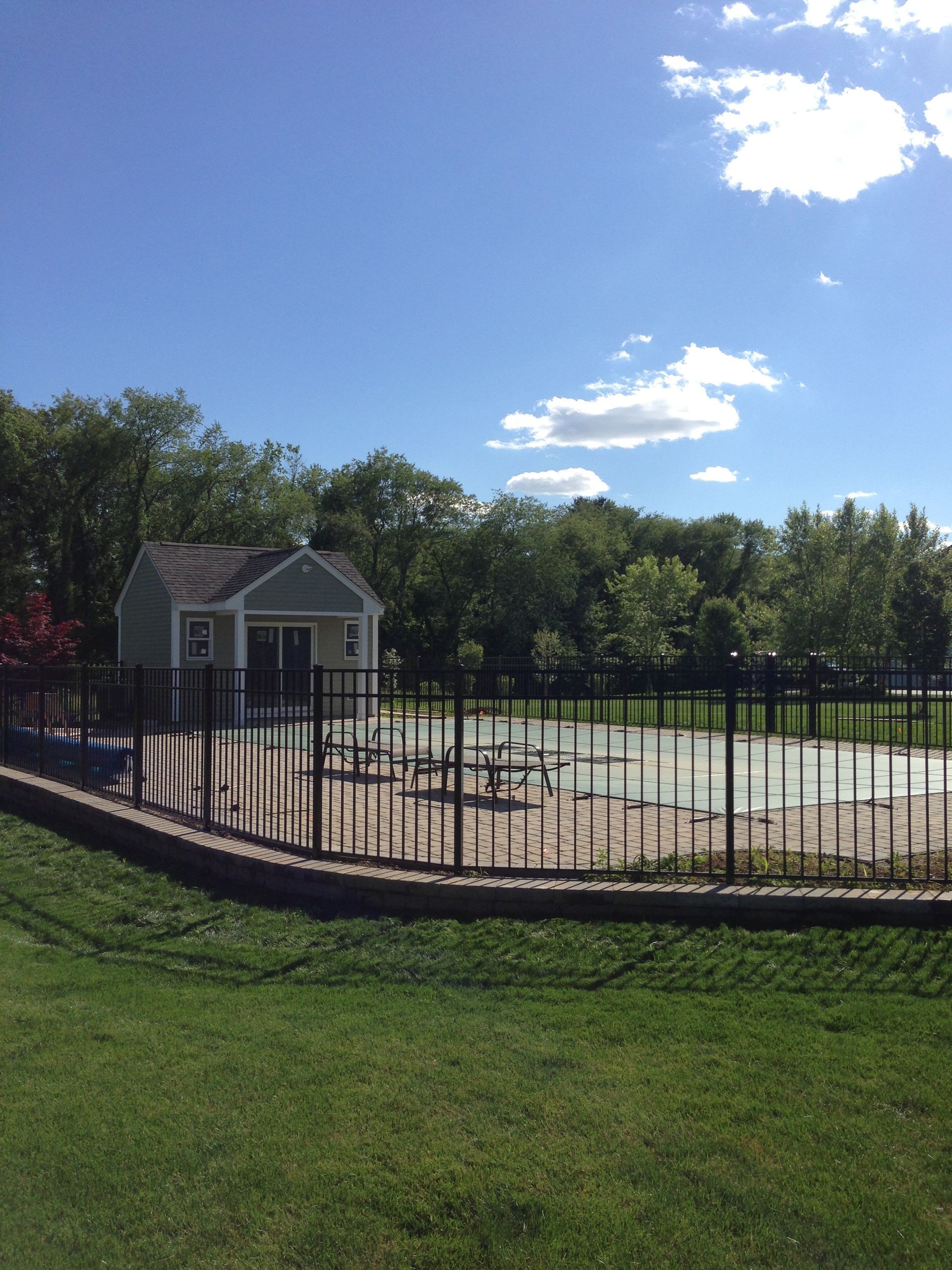 A fence surrounds a playground with a house in the background