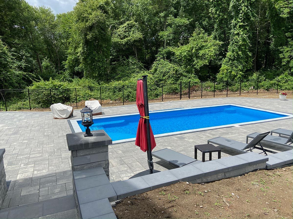 A large swimming pool in the backyard surrounded by a black fence