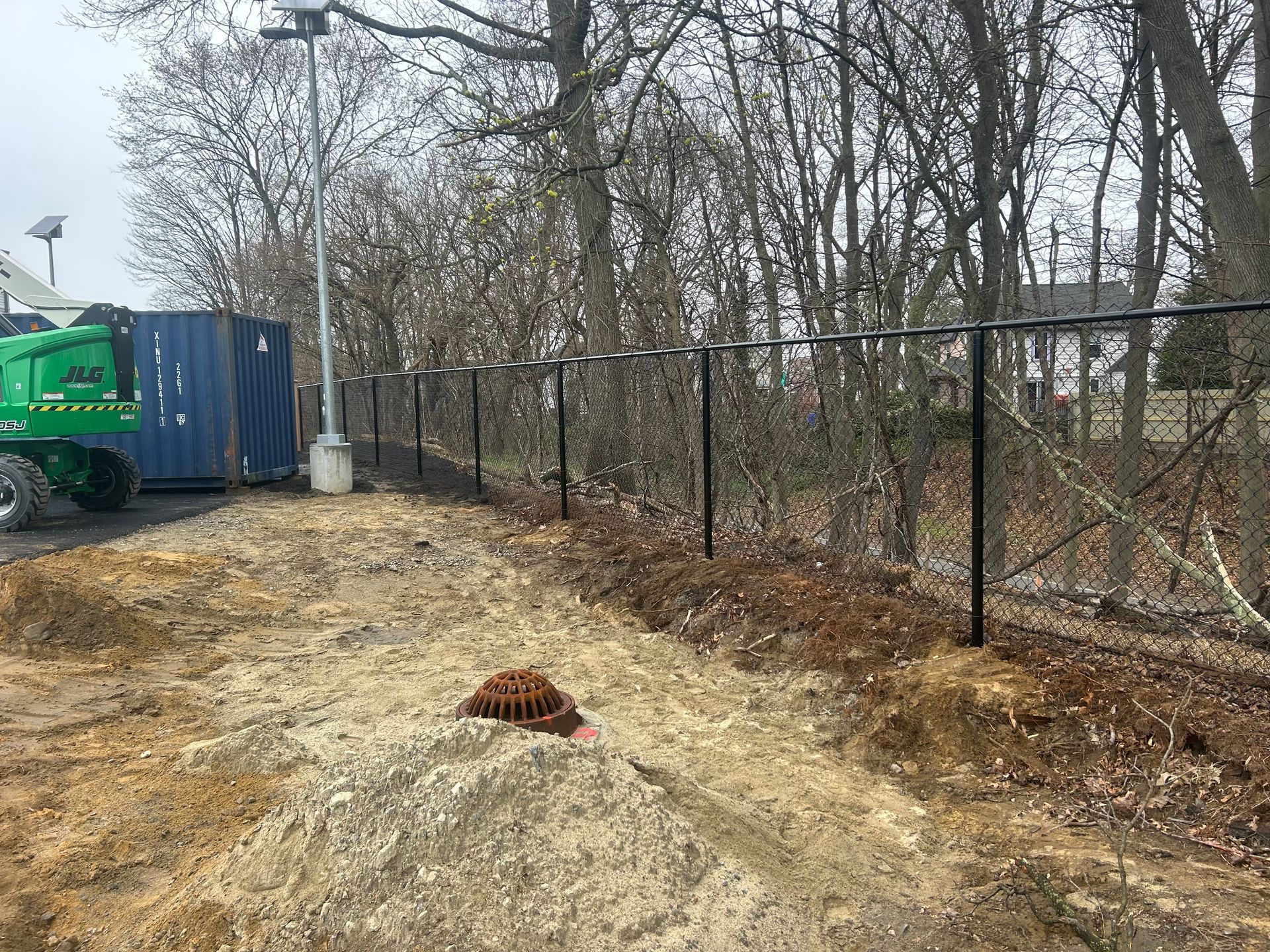 A chain link fence is being built in the middle of a forest.