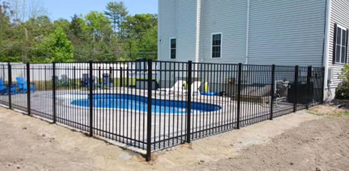 A black fence surrounds a swimming pool in a backyard