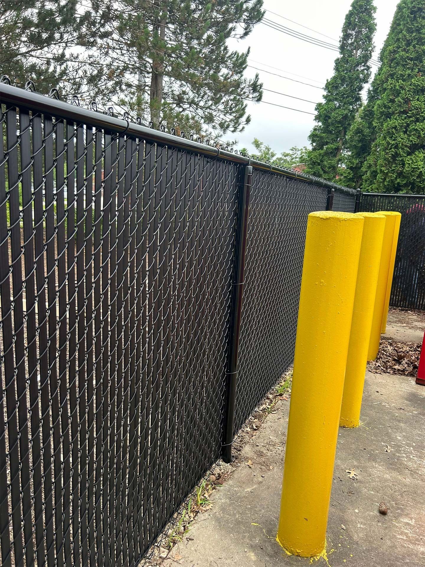 A chain link fence with yellow poles in front of it