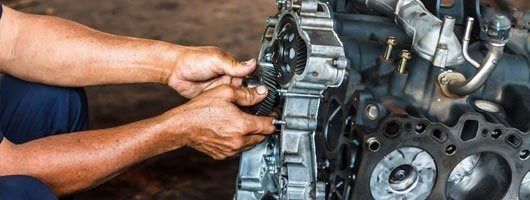 A man is working on a car engine with a wrench.