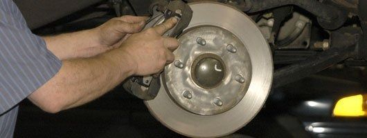 A man is fixing a brake disc on a car.