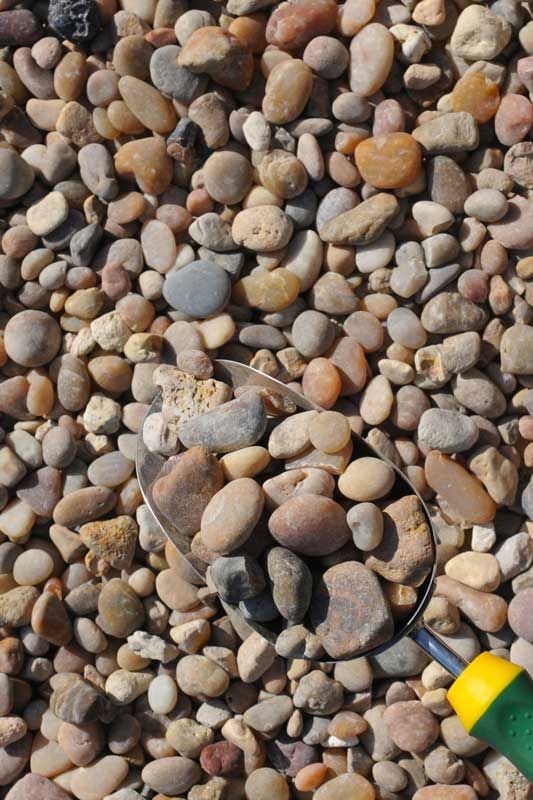 Scoop of smooth, mixed-color gravel.