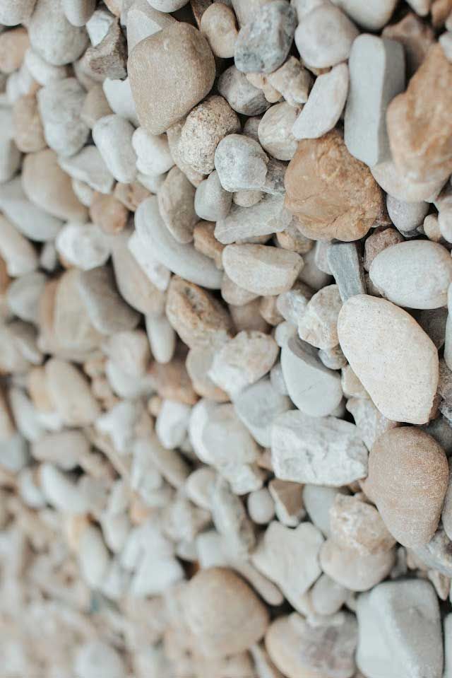 Close-up of a pile of small, smooth rocks in various shades of beige, white, and brown.