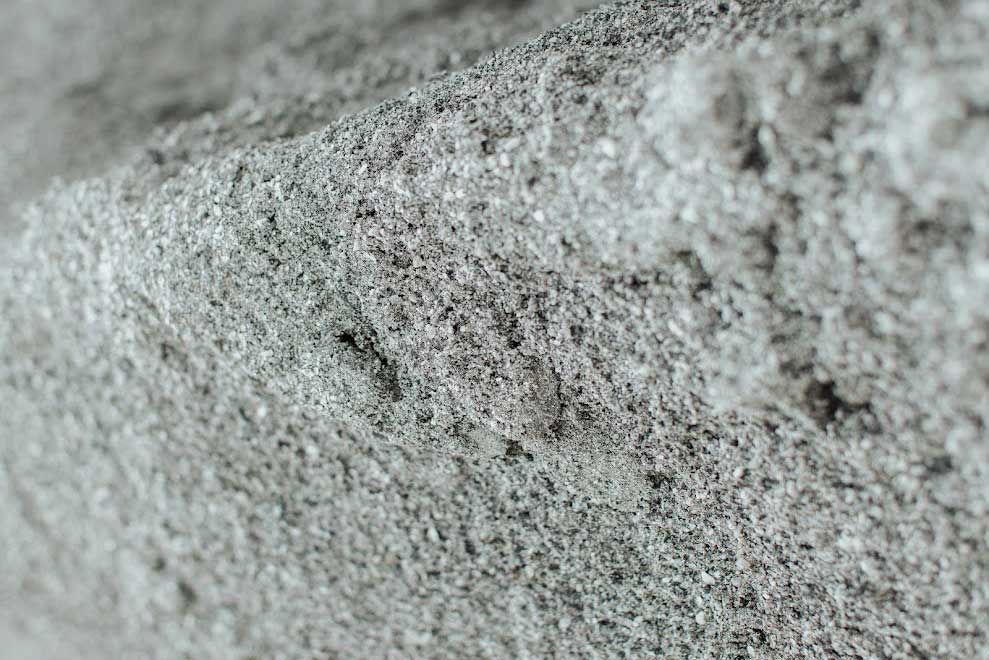 Close-up of a rough, textured gray material with visible fibers and uneven surface.