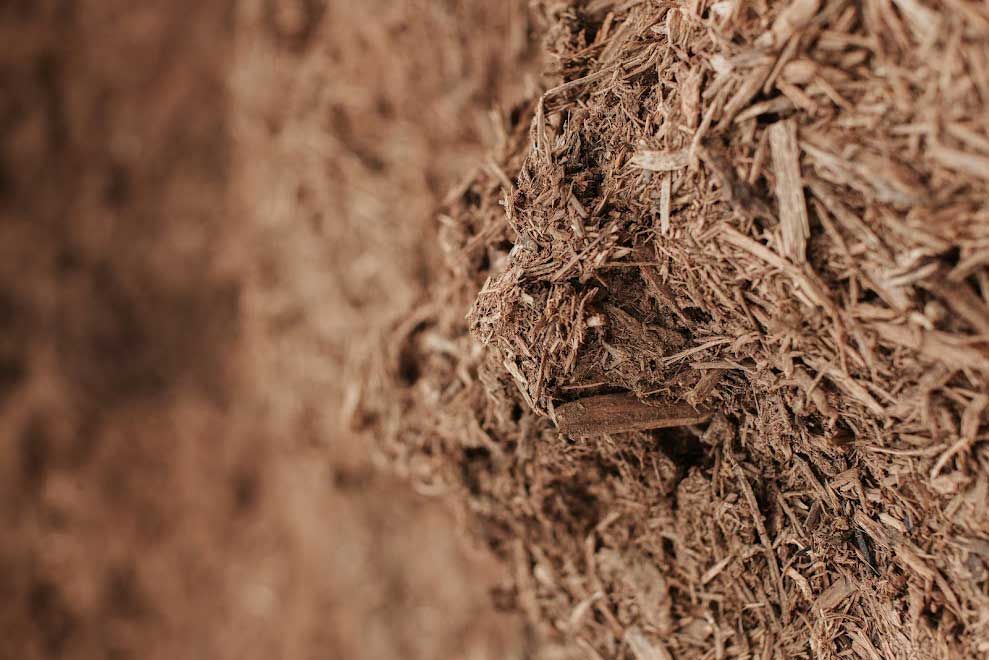 Pile of brown mulch, close-up texture, details of wood chips and fibers.