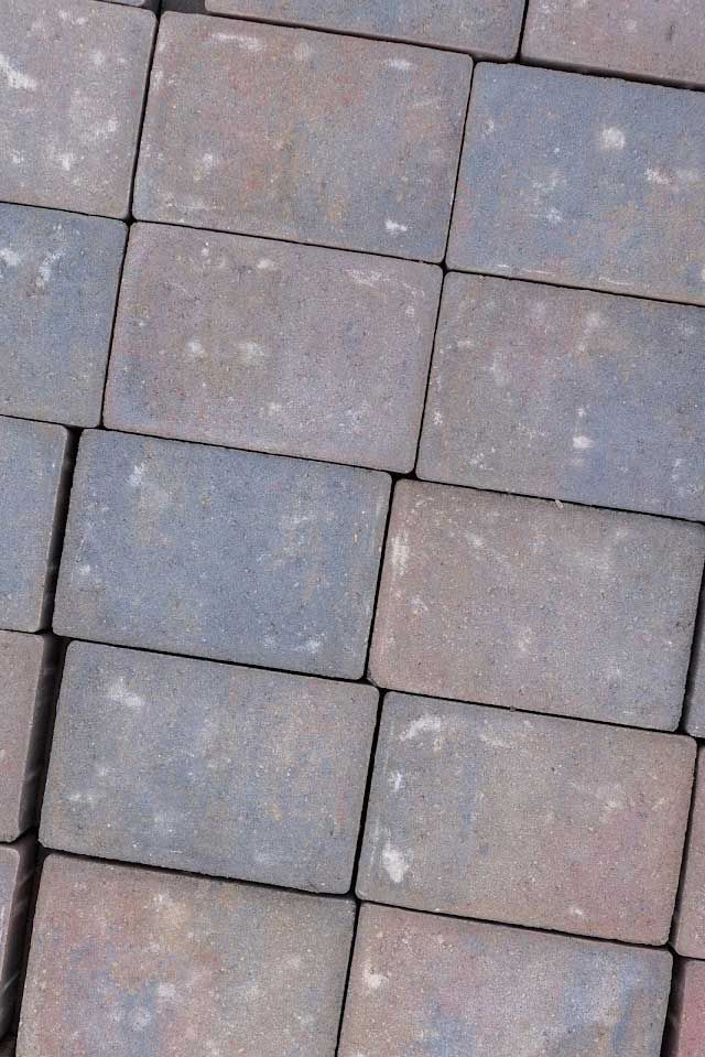 Rectangular paving stones, varying hues of gray, blue, and red, arranged in a grid pattern.